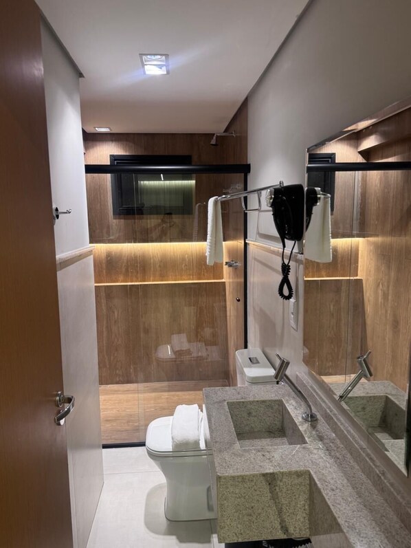 A modern bathroom with a toilet, sink, and mirror.