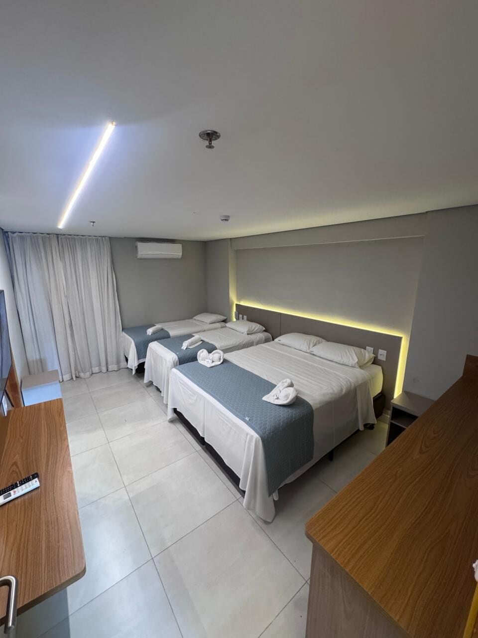 A hotel room with two beds, a desk, a chair, and a TV.