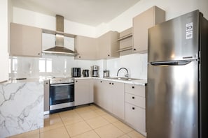 Eine moderne Küche mit einem Edelstahl-Kühlschrank, einem eingebauten Backofen und einer Dunstabzugshaube.