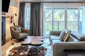 A modern living room with a sofa, armchair, coffee table, and a fireplace. - Condo 2 chambres - Ski in Ski out St Sau #206 (Saint-Sauveur)