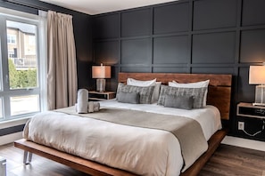 A modern hotel room with a large bed, a nightstand, a lamp, and a view of the outside. - Condo 2 chambres - Ski in Ski out St Sau #206 (Saint-Sauveur)