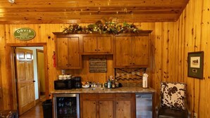 Interior de una cabaña de madera con una zona de cocina, un cartel que indica Orvis Wingshooting Lodge, y un cuadro enmarcado en la pared.