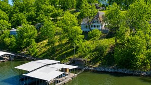 En fastighet vid en sjö med en brygga, ett hus och omgivande grönska.