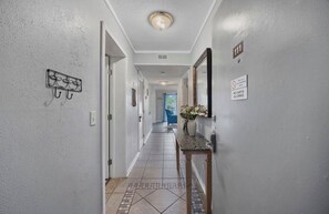 Ein Flur mit Fliesenboden, einer Wandleuchte, einer Tür mit einer Nummer und einem Schild mit der Aufschrift 'Keine Wagen erlaubt'.