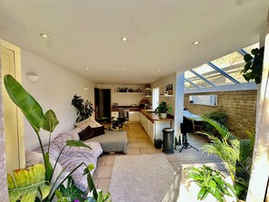 A spacious living area with a sofa, a dining table, and a kitchen in the background. - Spacious Garden Flat- Walk to Wimbledon (London)