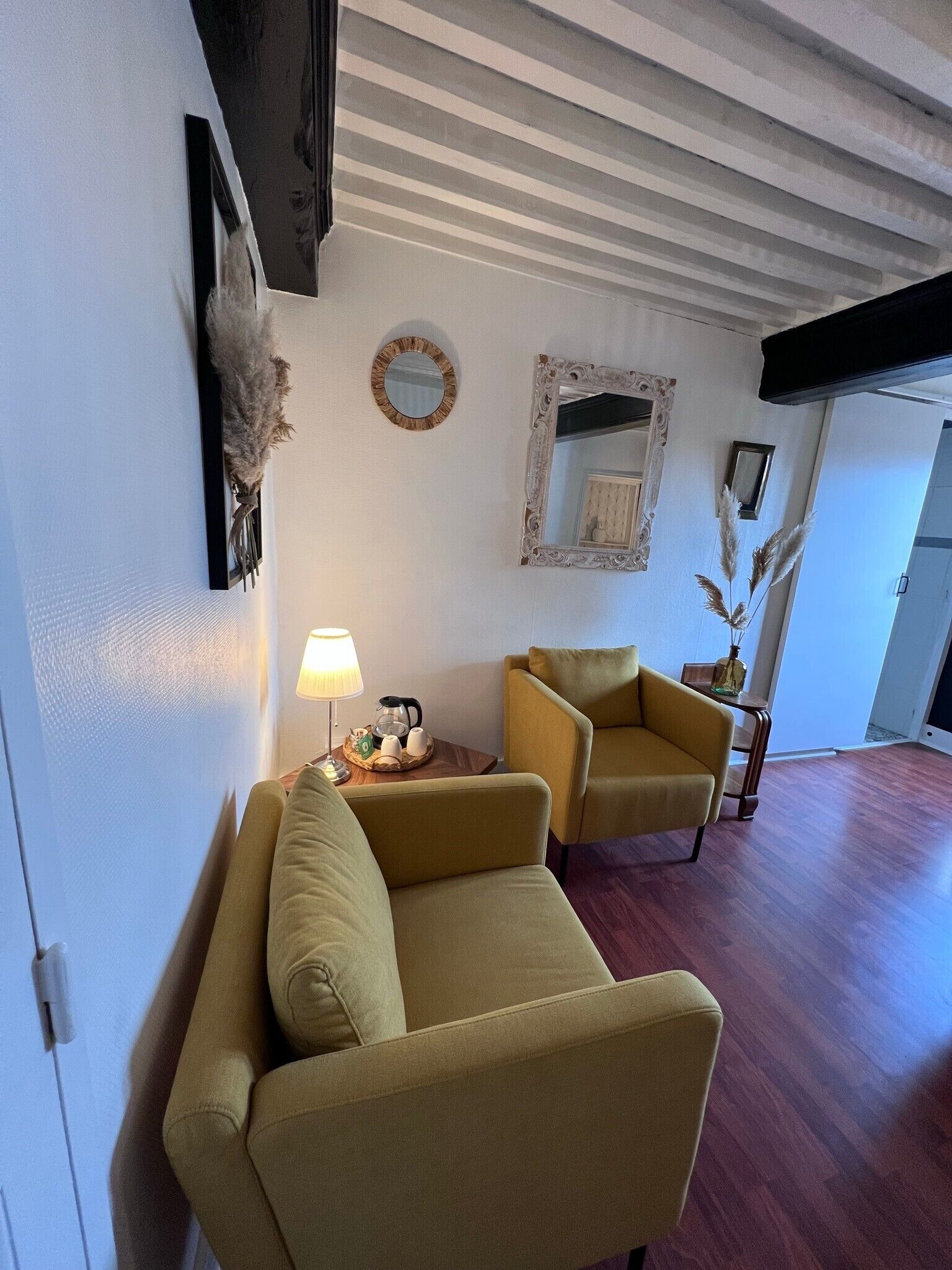 En stue med to lænestole, et sofabord, en lampe og pynt på væggen.