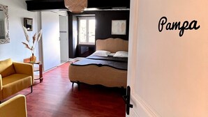 Une chambre à coucher avec un lit, un fauteuil jaune, un luminaire suspendu et une porte portant l’inscription « Pampa ».