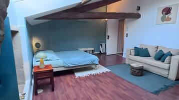 A bedroom with a bed, bedside table, lamp, and a view of the sky through a skylight.