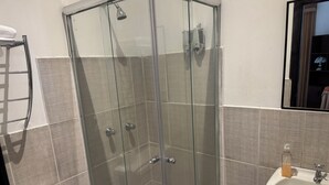 A glass-enclosed shower with a toilet and sink, a towel rack, and a mirror.