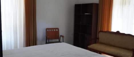 A room with a bed, a sofa, a chair, and a bookshelf.
