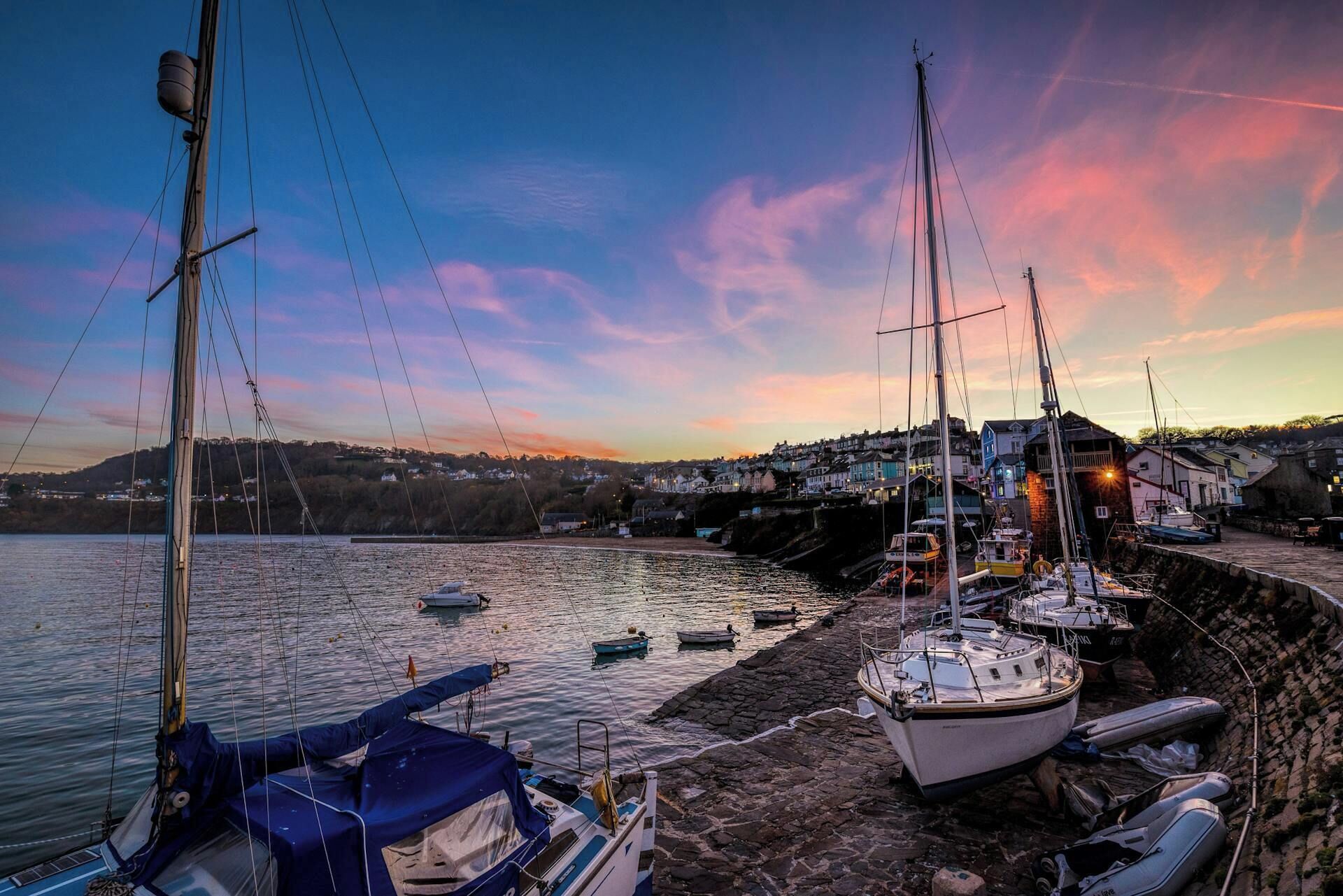 Harbour scene with yachts tied to the quay and calm water at sunset