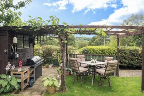 A patio with a grill, outdoor seating, and a pergola. - Cwm Llethi, New Quay (New Quay)