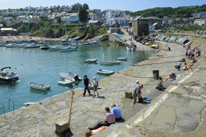A coastal town with a stone quay, boats, and people. - Cwm Llethi, New Quay (New Quay)