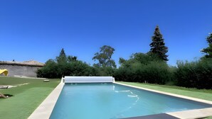 A rectangular swimming pool with a clear blue sky above and a green lawn surrounding it. - Standard Room “La Marine” (Senozan)