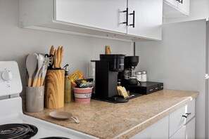 Una cocina equipada con cafetera, utensilios, especias y microondas.