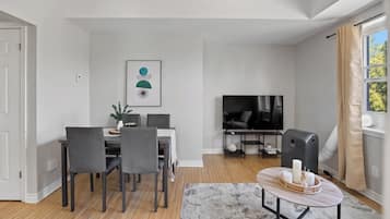 Een moderne woonkamer met een eethoek, een flatscreen televisie en een open haard.