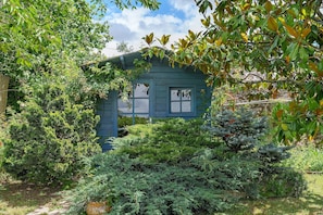 A small blue house surrounded by dense greenery.