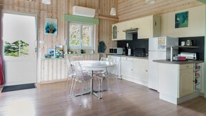 A wooden-paneled kitchen with a dining table and chairs, white cabinets, and a window.
