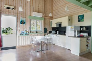 A wooden-paneled kitchen with a dining table and chairs, white cabinets, and a window.