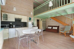 A wooden interior with a dining table, chairs, a kitchen, and a staircase.
