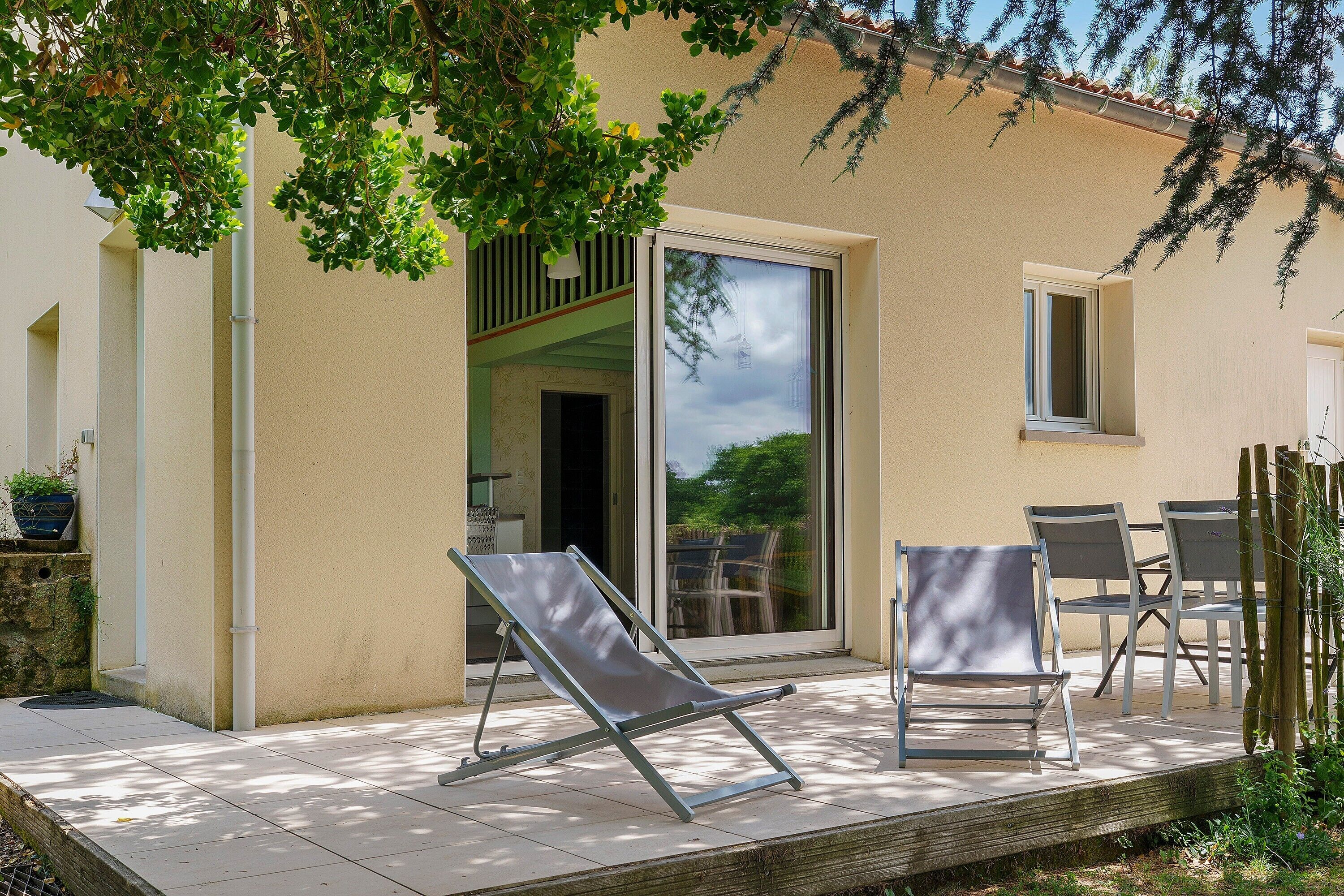 Un patio con puerta corredera de vidrio, dos sillones y una mesa con sillas.