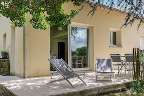 A patio with a sliding glass door, two lounge chairs, and a table with chairs.