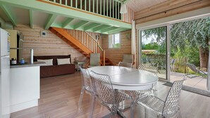 A wooden interior with a dining area, staircase, and a view of the outdoors.