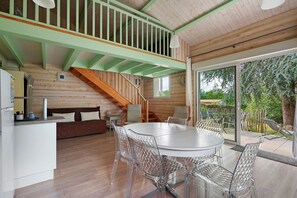 A wooden interior with a dining area, staircase, and a view of the outdoors.