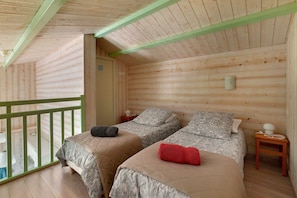 A cabin with two beds, a balcony, and wooden walls.