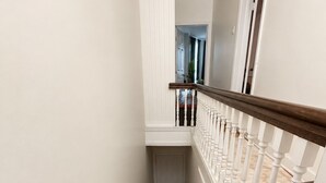 Una escalera de madera con paredes y una puerta blanca en la parte superior.