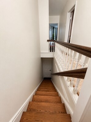 Eine Holztreppe mit weißen Wänden und einer weißen Tür oben.