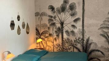 A bedroom with a bed, a nightstand, a lamp, and a wall mural.