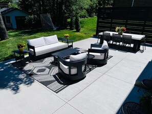 An outdoor patio with a sofa, round seating, a table, and chairs.