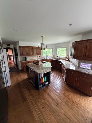 A modern kitchen with wooden cabinets, a central island, and a built-in oven.