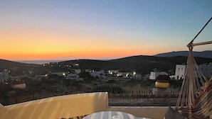 A terrace with a round table and chairs, overlooking a landscape with buildings and hills. - Alexandras studios  (Irakleia)