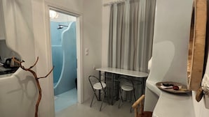 A modern interior with a dining area, a shower, and a unique wall-mounted mirror. - Alexandras studios  (Irakleia)