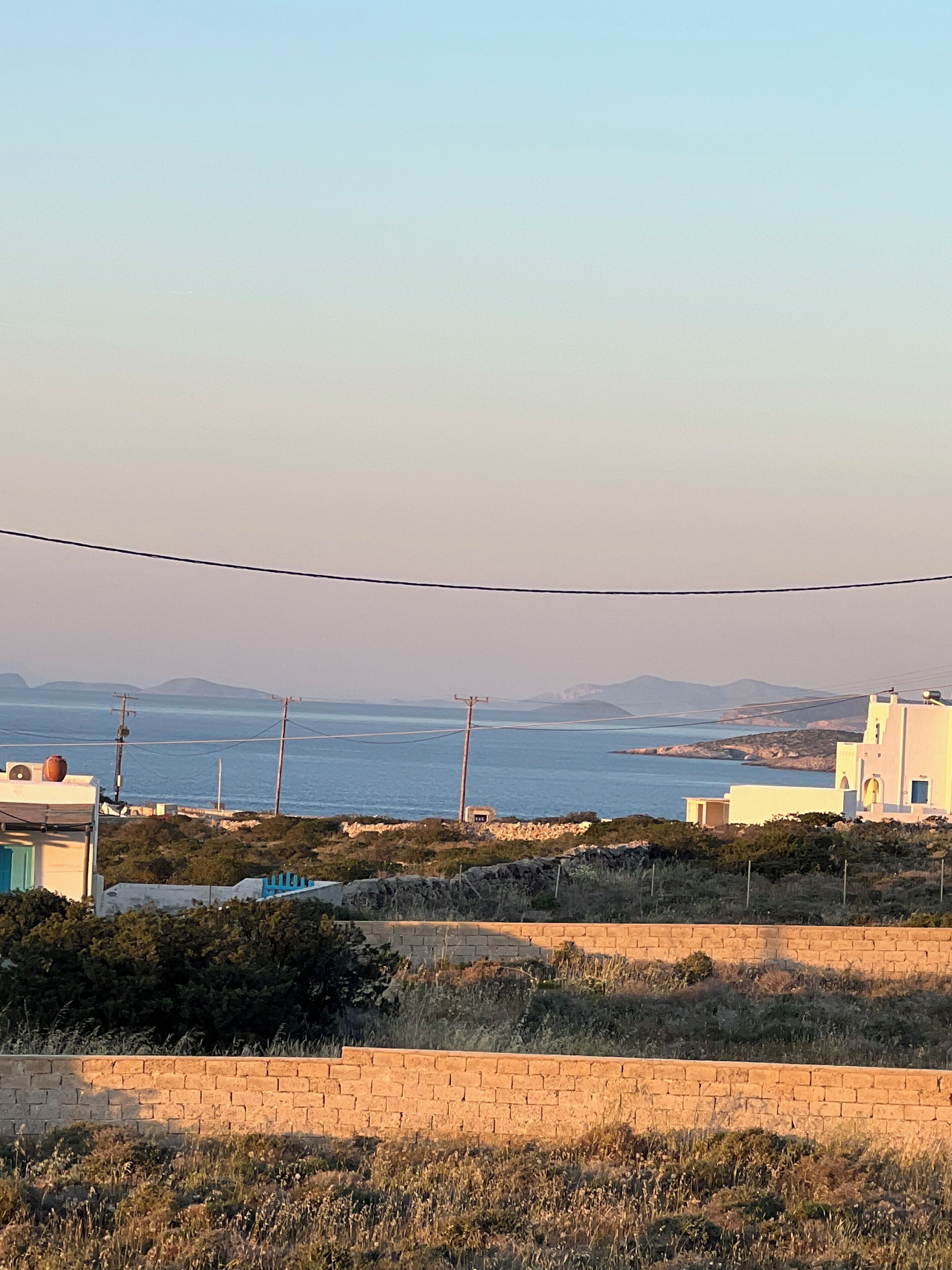 A coastal landscape with buildings, a clear sky, and a view of the sea.