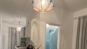 A modern kitchen with a central island, a dining area with a table and chairs, and a hallway leading to a bathroom. - Alexandras studios  (Irakleia)
