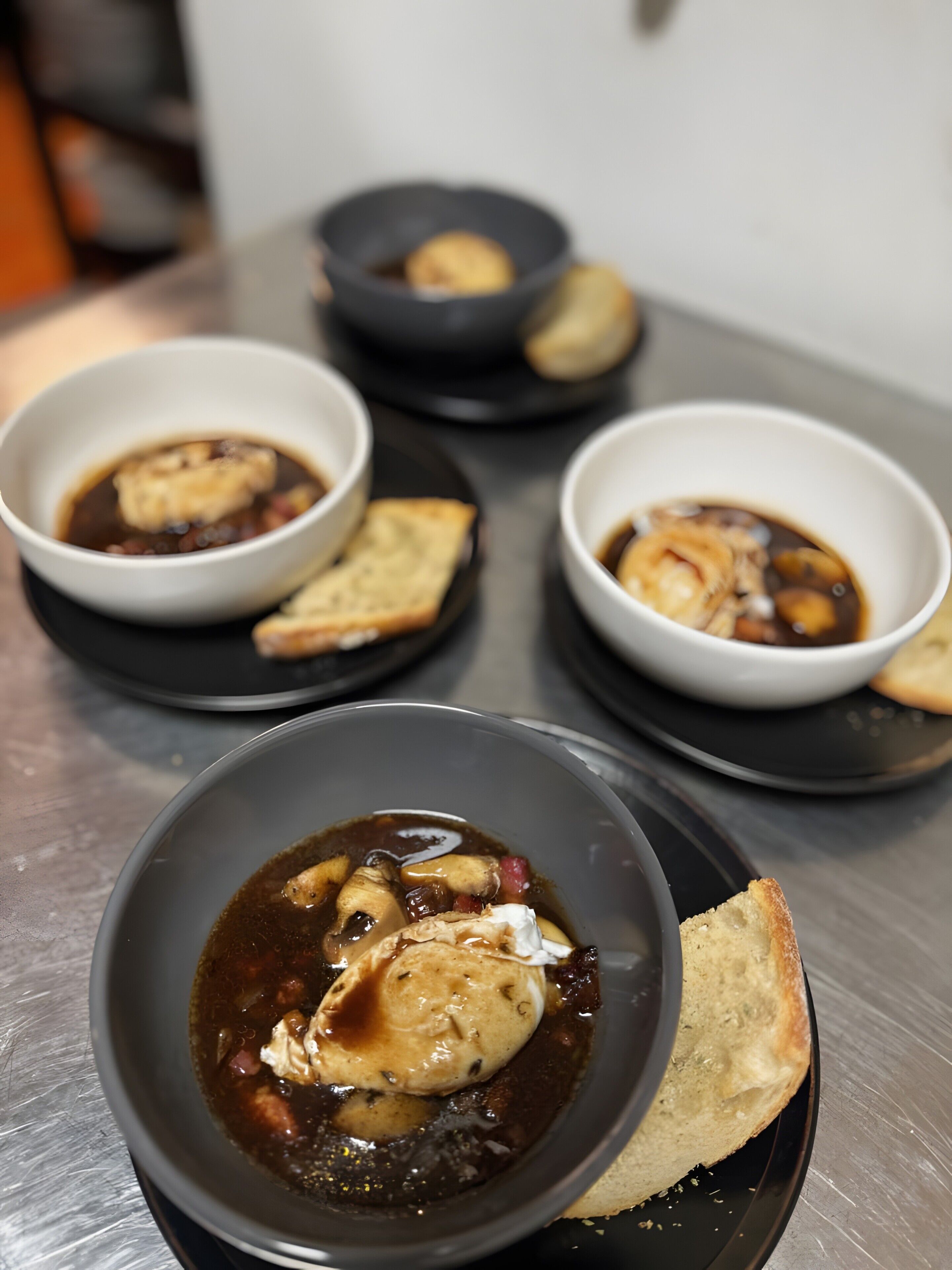 Tres tazones de sopa con pan sobre una mesa.