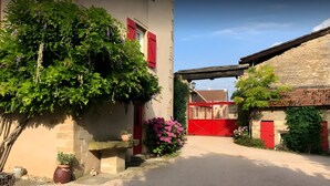 A narrow street with buildings on either side, a red gate, and a stone wall.