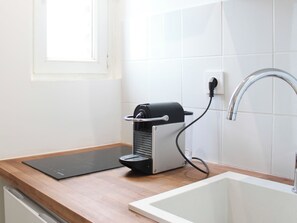 Eine Küche mit Arbeitsplatte, einer Kaffeemaschine, einem Spülbecken und einem Fenster.