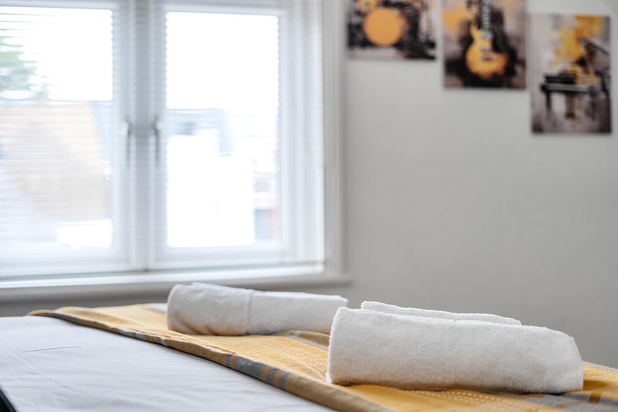 Um quarto com uma cama, janela e obras de arte nas paredes.