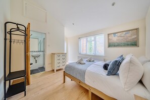 A bedroom with a bed, a dresser, a wardrobe, a window with a view, and a painting on the wall. - Stylish 2Bed Flat Near Hampton Court & RiverThames - Pass the Keys (East Molesey)