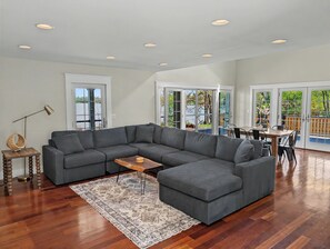 A spacious living room with a sectional sofa, a wooden coffee table, and a patterned rug. - Riverside at Pear Tree Point--Waterfront Escape (Chestertown)
