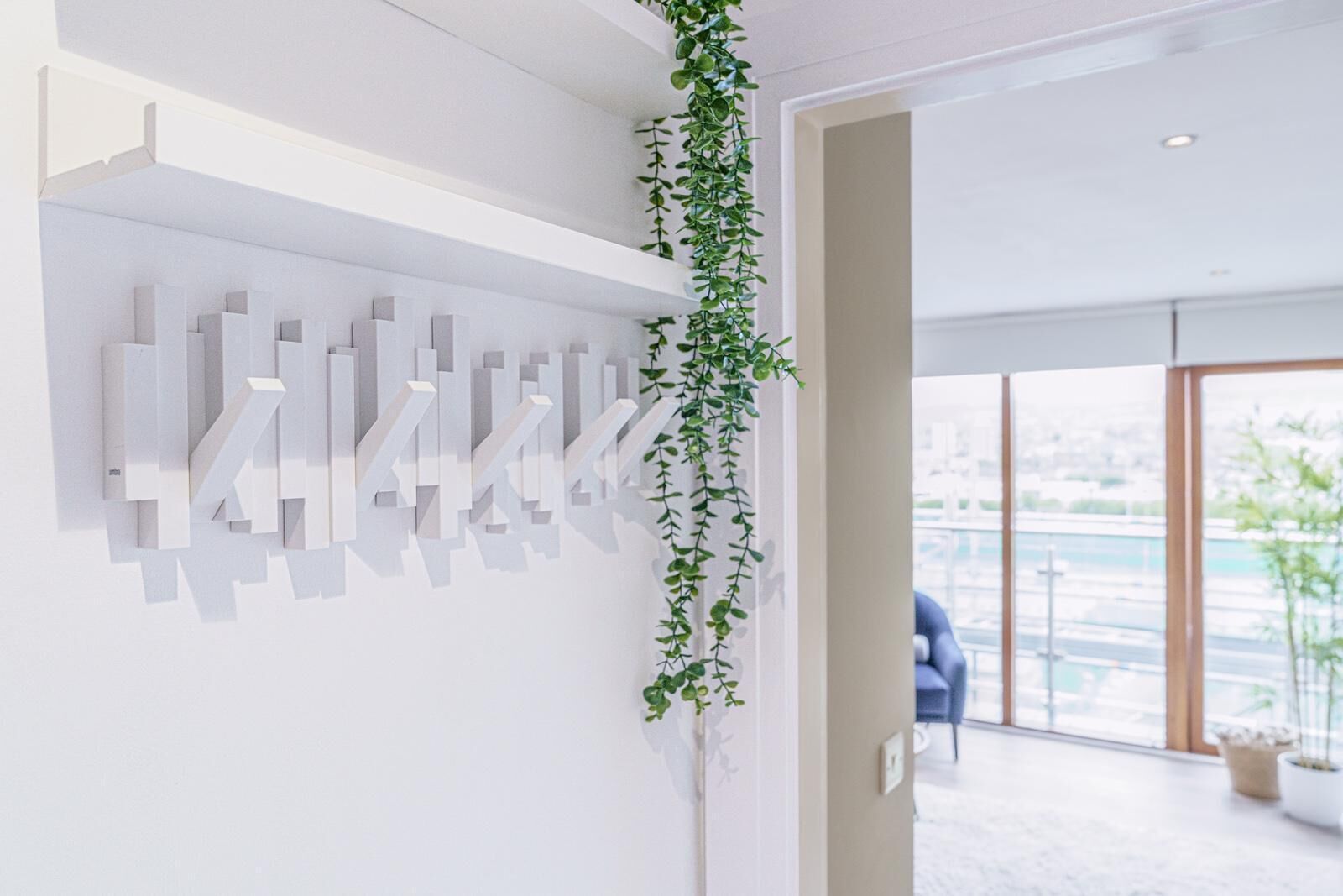 A modern interior with a white wall, abstract art, and a hanging plant.