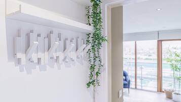A modern interior with a white wall, abstract art, and a hanging plant.