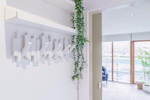 Ein modernes Interieur mit einer weißen Wand, abstrakter Kunst und einer hängenden Pflanze.
