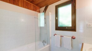 Une salle de bain avec une douche à parois de verre, un plafond en bois et une fenêtre au-dessus du lavabo.