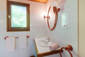 Une salle de bain avec une fenêtre, un lavabo, un miroir et deux serviettes sur un porte-serviettes.