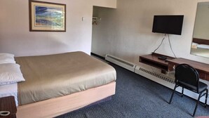 A hotel room with a bed, a desk, a chair, a television, and a painting on the wall. - Algonquin Motor Lodge (Edmonton)